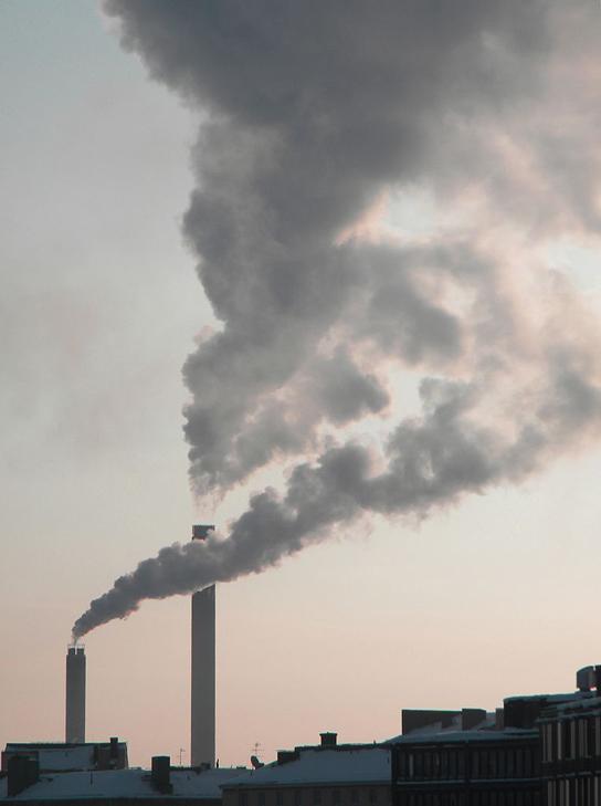 This photo shows a smokestack from a factory churning gray smoke into the air.