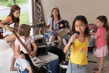 Image of young girls playing instruments in a garage