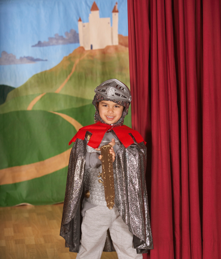 Image of young boy in costume on stage with painted backdrop