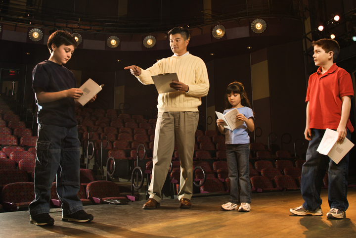 Image of a group of students on stage with their teacher